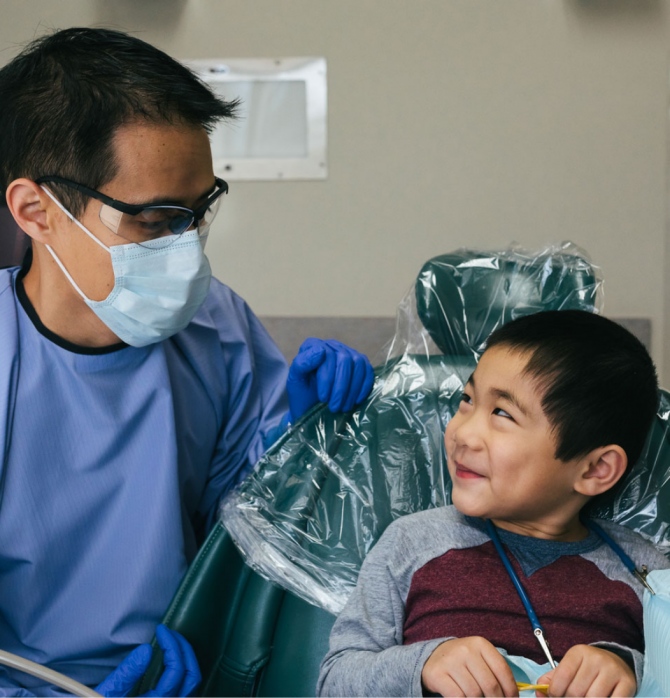 Dentist in mask looking at child patient