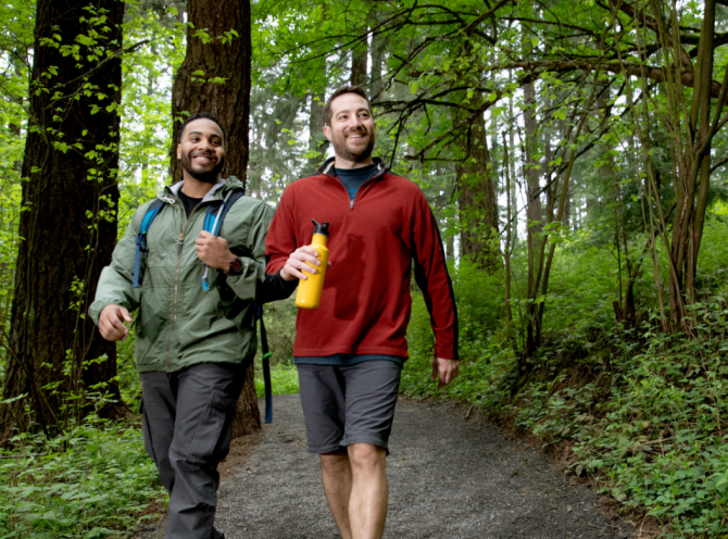 Two people smiling and walking in a forest
